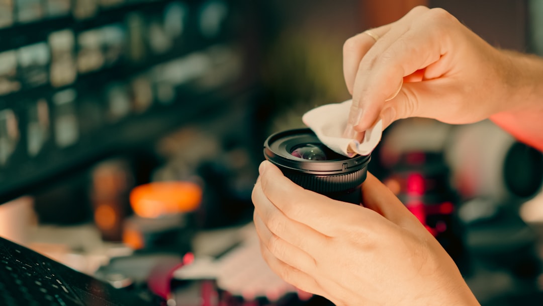 Cleaning camera lens maintenance photographer hands. Close-up of man cleaning DSLR lens with microfiber cloth